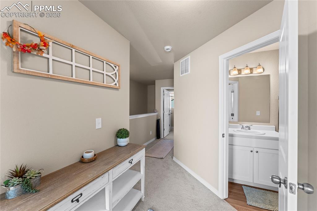 Image 29 of 37: The upper hallway provides a useful transition space with room for furnitur