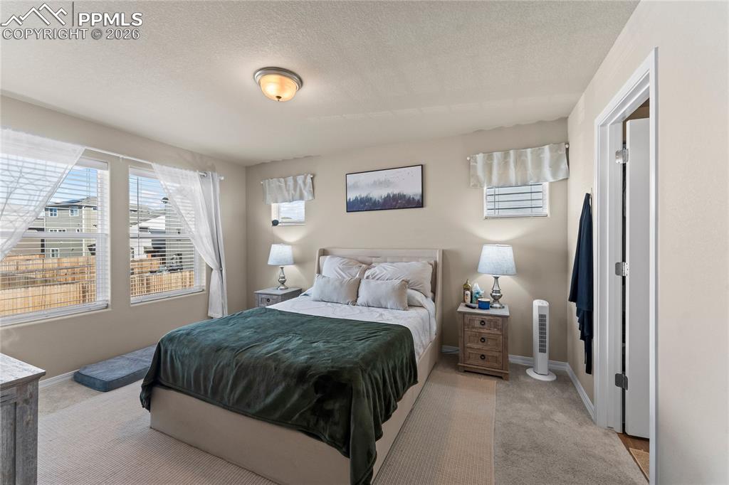 Image 3 of 37: The primary bedroom feels soft and inviting, with natural light and gentle