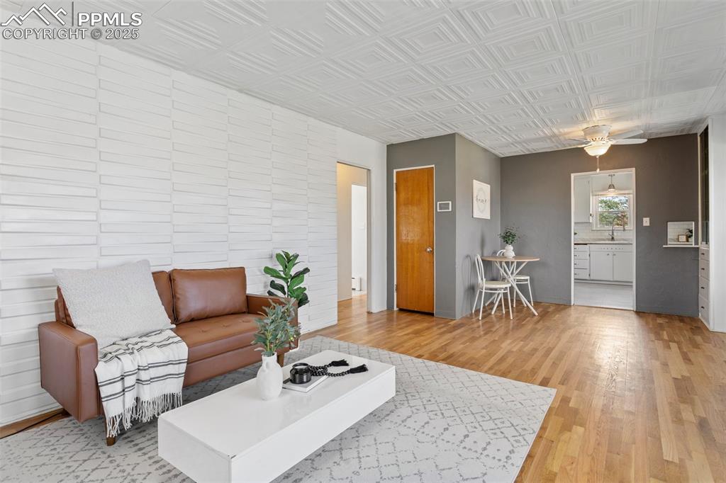 Image 11 of 37: Living area with an ornate ceiling, a ceiling fan, and light wood-type floo
