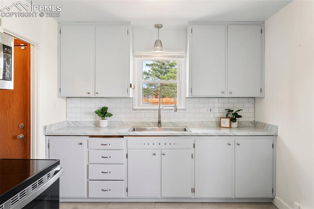 Image 14 of 37: Kitchen featuring white cabinets, decorative backsplash, and a sink