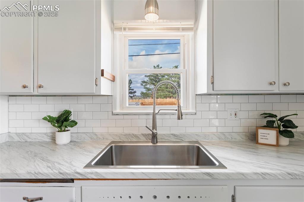 Image 15 of 37: Kitchen with light countertops, a sink, and tasteful backsplash