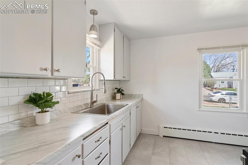 Image 16 of 37: Kitchen featuring backsplash, a wealth of natural light, baseboard heating,