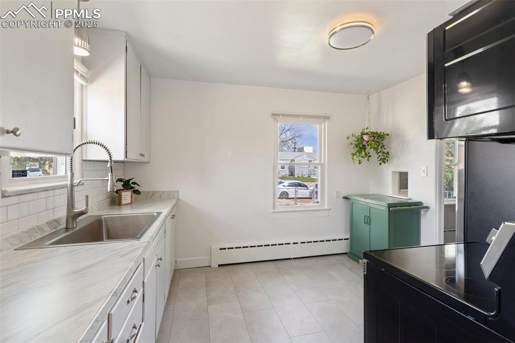 Image 17 of 37: Kitchen with light countertops, a sink, black range with electric cooktop,