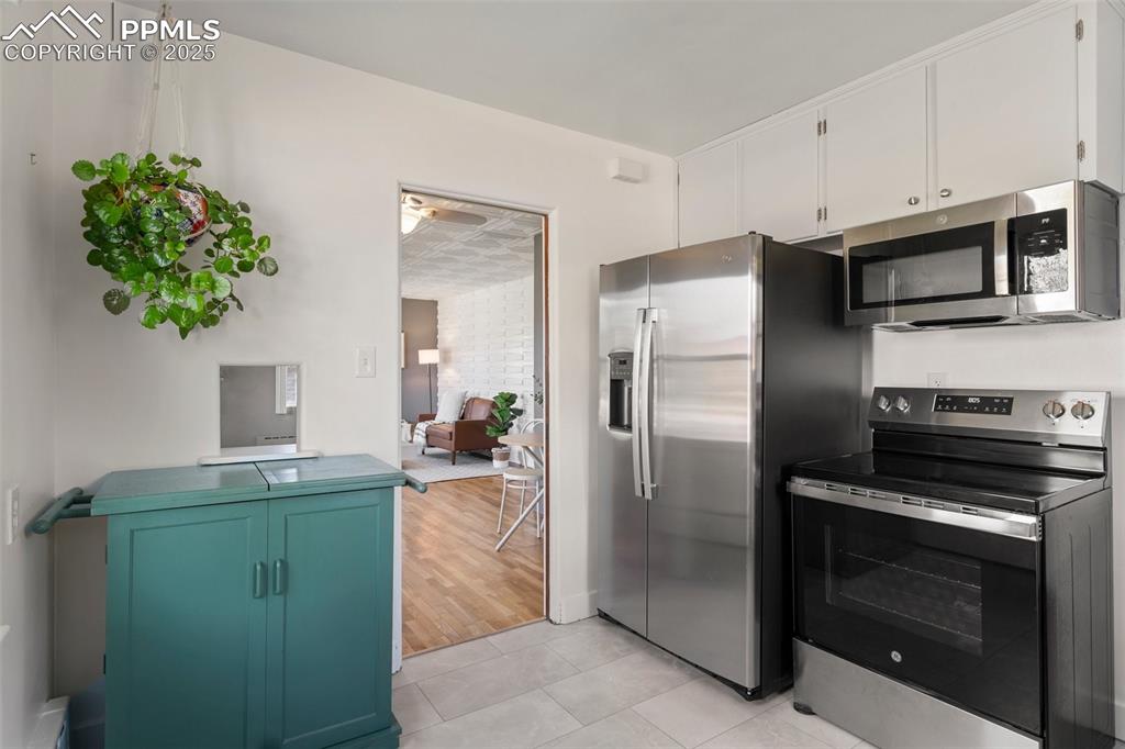 Image 18 of 37: Kitchen with a ceiling fan, white cabinetry, stainless steel appliances, an