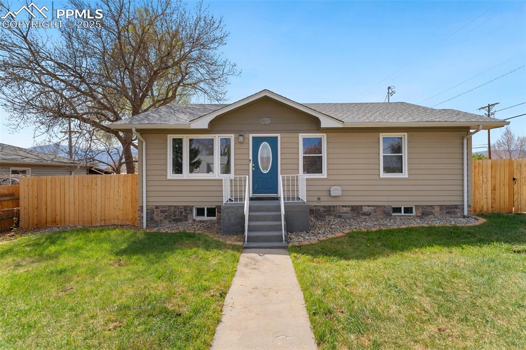 Image 2 of 37: Bungalow with fence, a shingled roof, and a front lawn