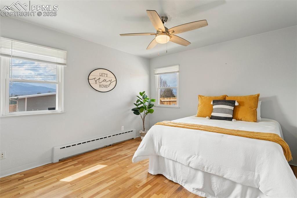 Image 20 of 37: Main level bedroom featuring baseboard heating, wood finished floors, and a