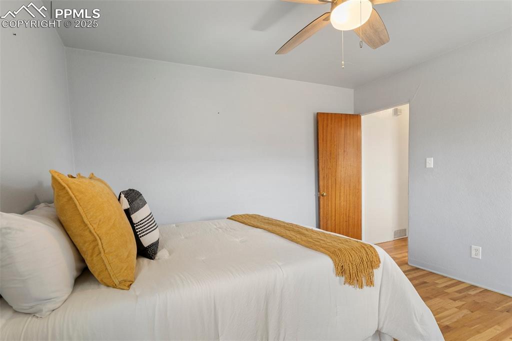 Image 21 of 37: Main level bedroom featuring a ceiling fan and wood finished floors