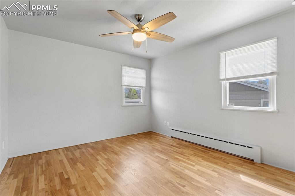 Image 23 of 37: Main level bedroom with baseboard heating, ceiling fan, and wood finished f