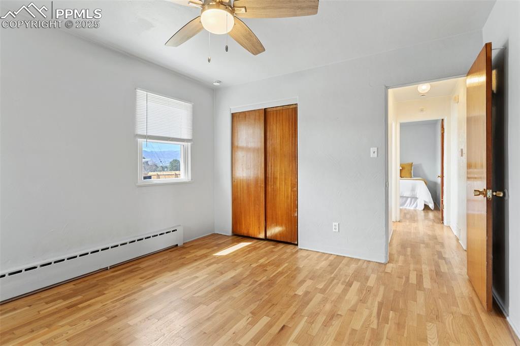 Image 24 of 37: Main level bedroom featuring baseboard heating, a ceiling fan, a closet, an