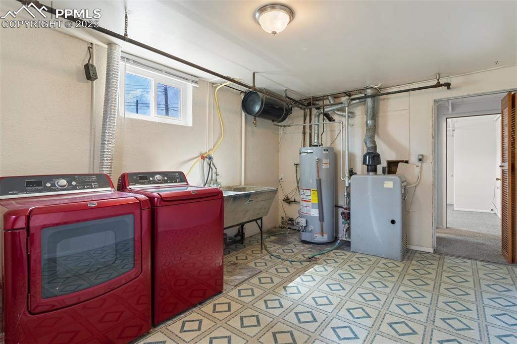 Image 33 of 37: Laundry area with washing machine and dryer, gas water heater, tile pattern