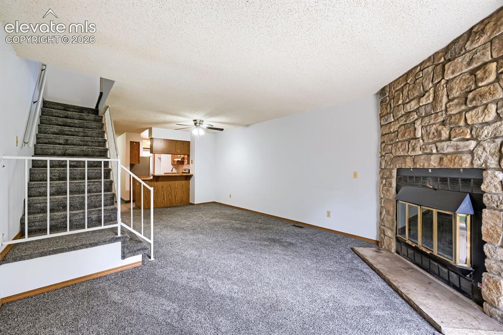 Image 10 of 23: Stone-front fireplace with a black insert, open-concept living area, and a 