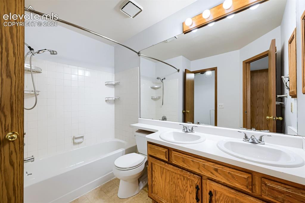 Image 16 of 23: Bathroom featuring a dual vanity with white oval sinks, a built-in bathtub 