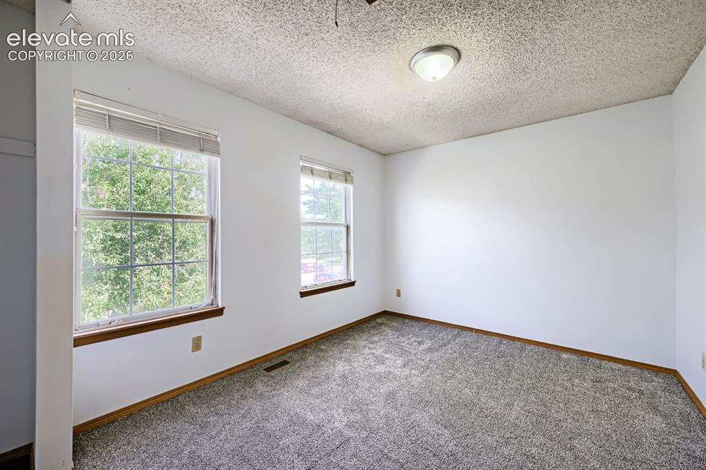 Image 17 of 23: Two large windows, textured ceiling, flush mount lighting, light gray carpe