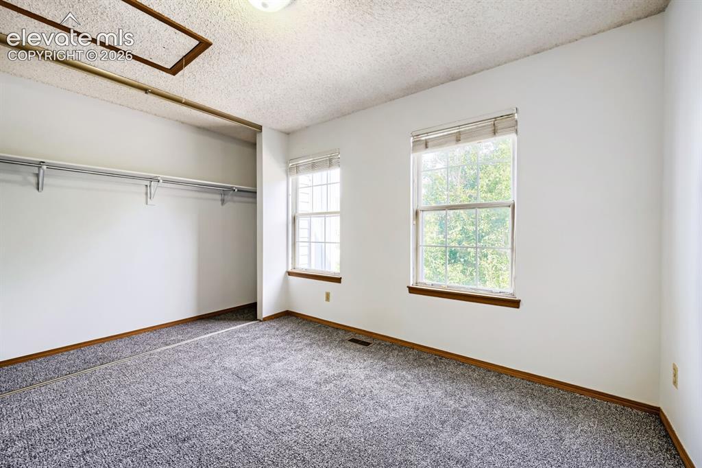 Image 18 of 23: Room with carpet flooring, two windows, and an integrated closet system