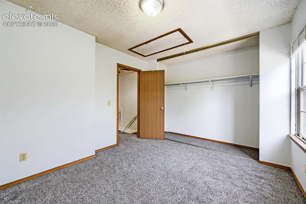 Image 19 of 23: Wall-to-wall carpeting with light-toned trim, a built-in closet with hangin
