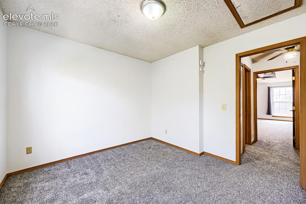Image 20 of 23: Gray textured carpeting, white painted walls, and wood-trim doorways
