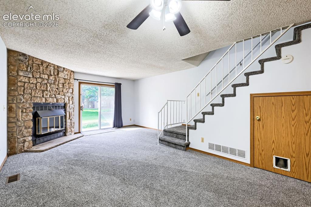 Image 3 of 23: Stone-faced fireplace, ceiling fan with integrated lighting, sliding glass 