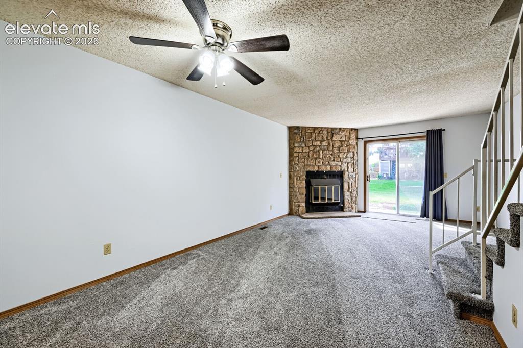 Image 4 of 23: Carpeted living space featuring a stone-clad fireplace and hearth