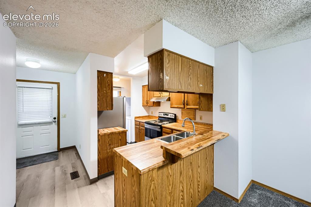 Image 7 of 23: Kitchen featuring wood cabinetry, stainless steel sink, and wood-finish cou