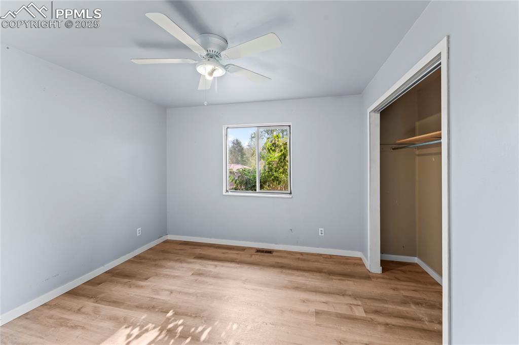 Image 12 of 36: Unfurnished bedroom featuring wood finished floors, a ceiling fan, and a cl