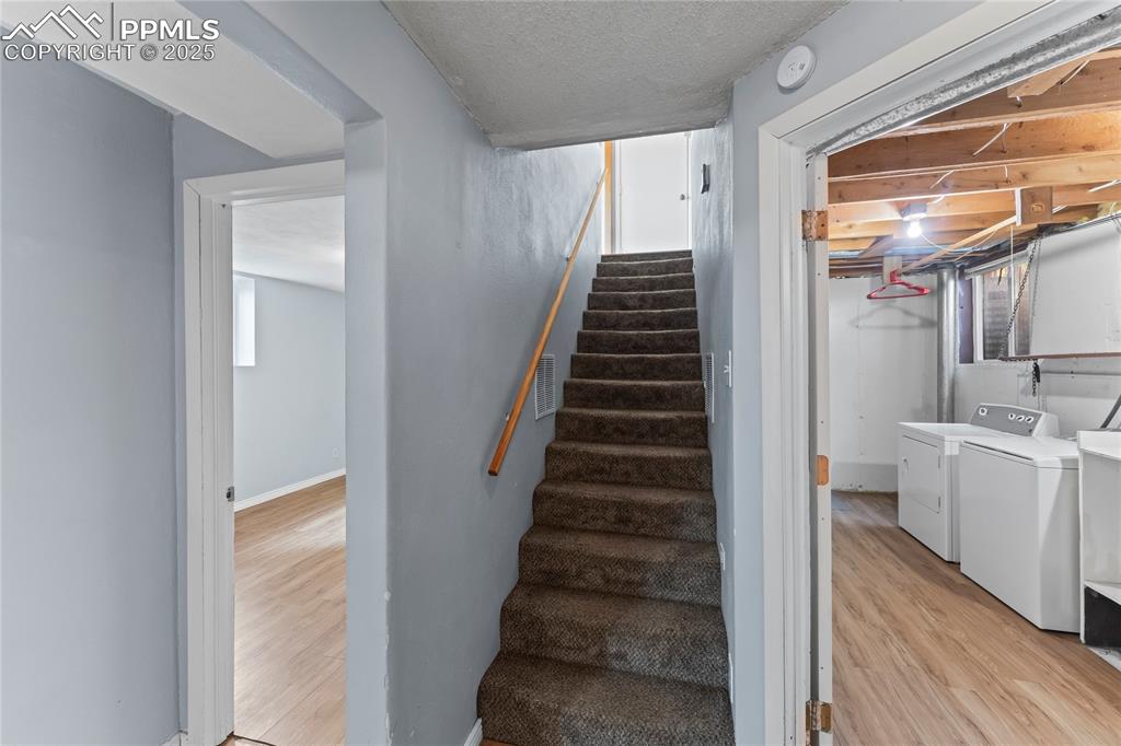 Image 16 of 36: Staircase with wood finished floors, washer and clothes dryer, and a textur