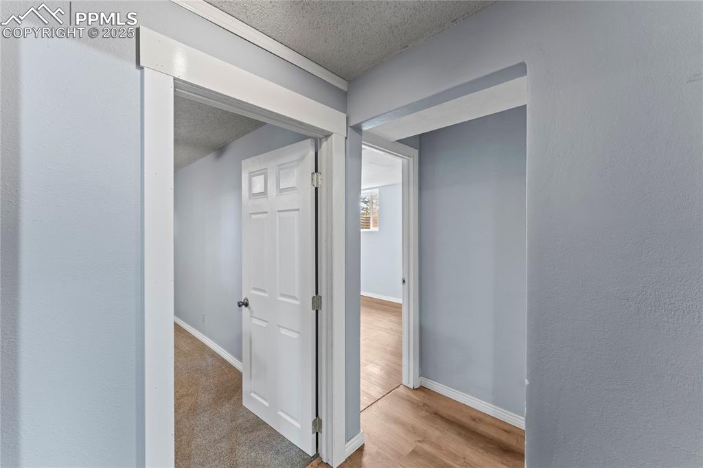 Image 17 of 36: Hallway with a textured ceiling, wood finished floors, and a textured wall