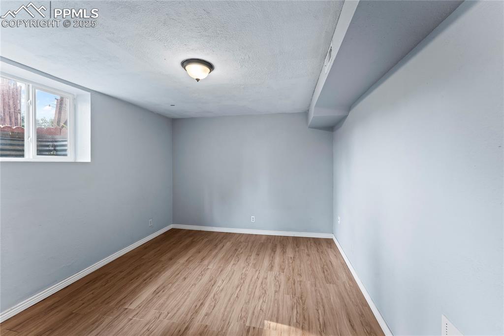 Image 20 of 36: Empty room featuring a textured ceiling and wood finished floors