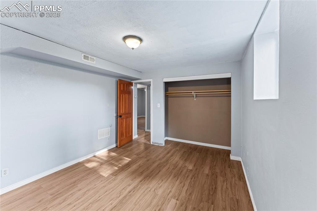 Image 21 of 36: Unfurnished bedroom with wood finished floors, a closet, and a textured cei