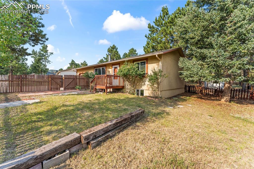Image 31 of 36: Back of house featuring a fenced backyard, stucco siding, and a wooden deck