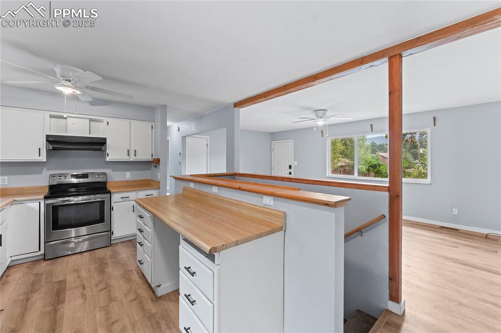 Image 7 of 36: Kitchen featuring a ceiling fan, stainless steel electric stove, and light 