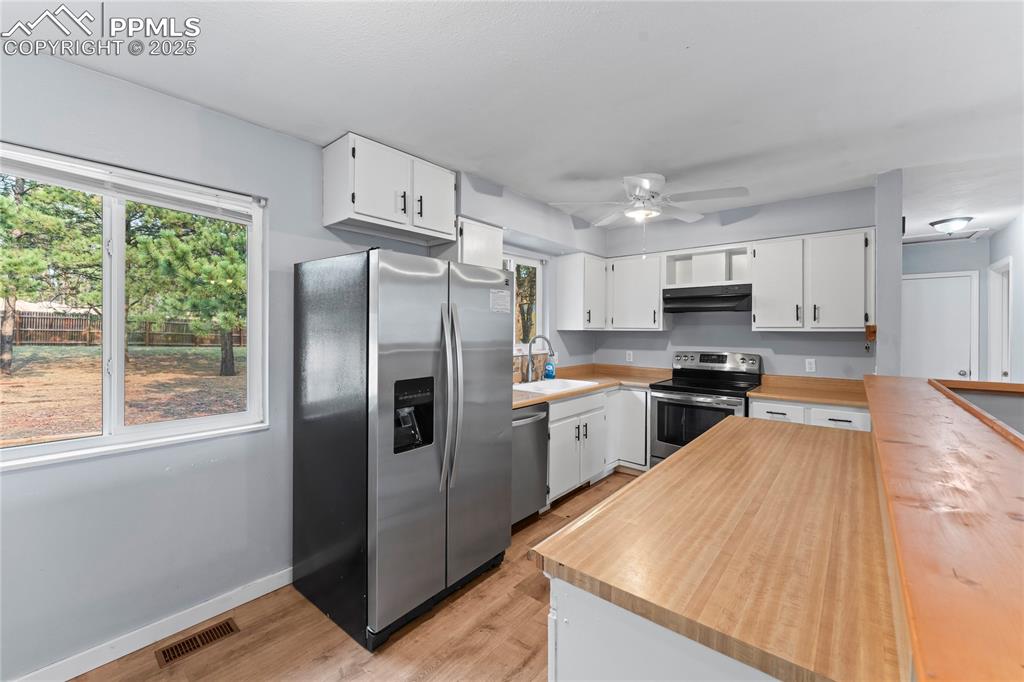 Image 8 of 36: Kitchen with stainless steel appliances, light wood-style flooring, white c