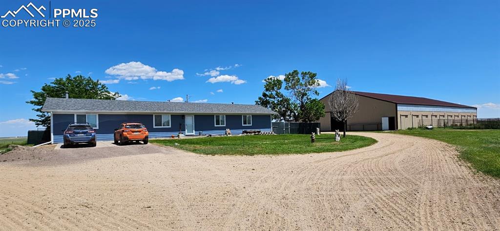 Caption: Single story home with dirt driveway, an outdoor structure, and an outbuilding