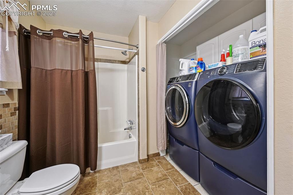 Image 10 of 43: Laundry room with tile patterned floors and washing machine and clothes dry