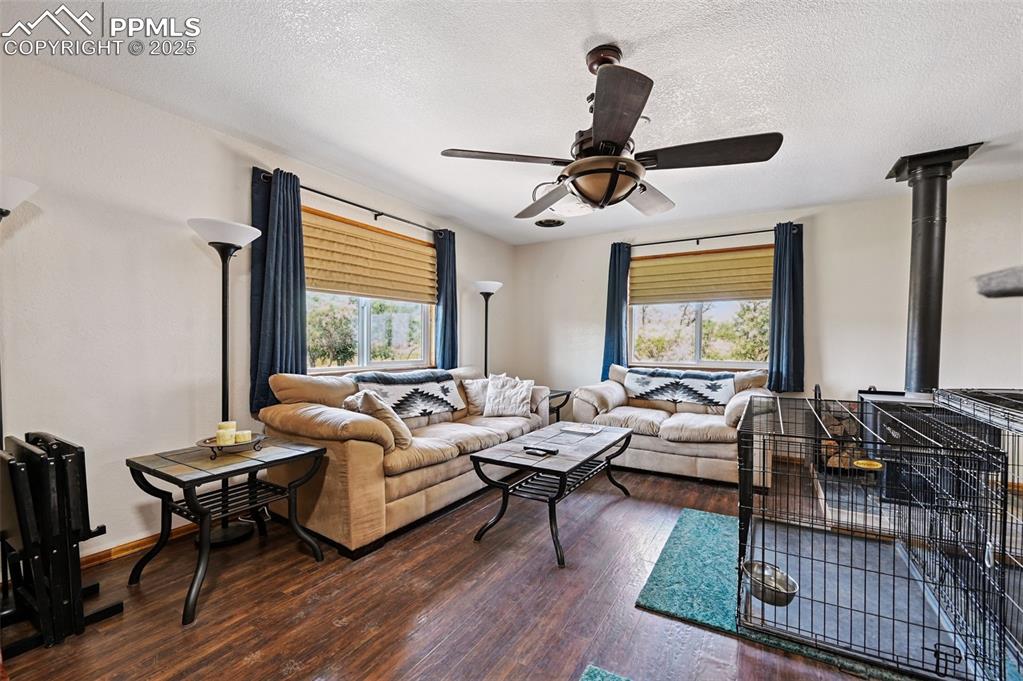 Image 13 of 43: Living area with a wood stove, a textured ceiling, dark wood-type flooring,