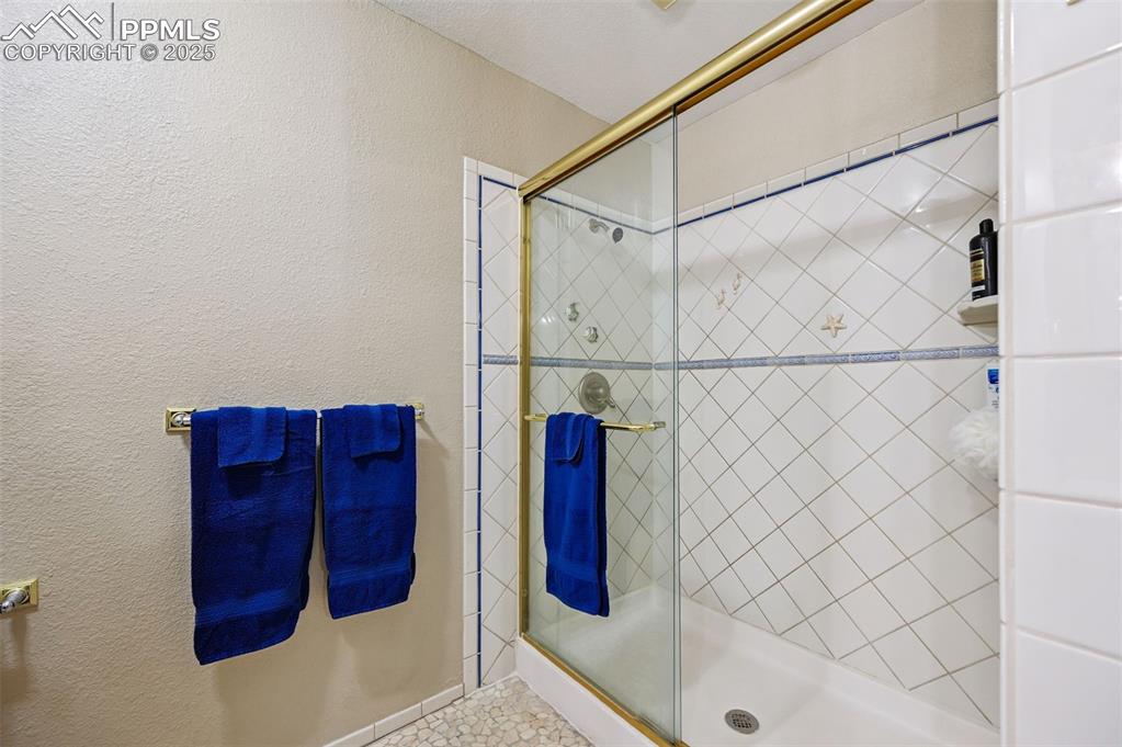 Image 25 of 43: Full bath with a textured wall and a shower stall