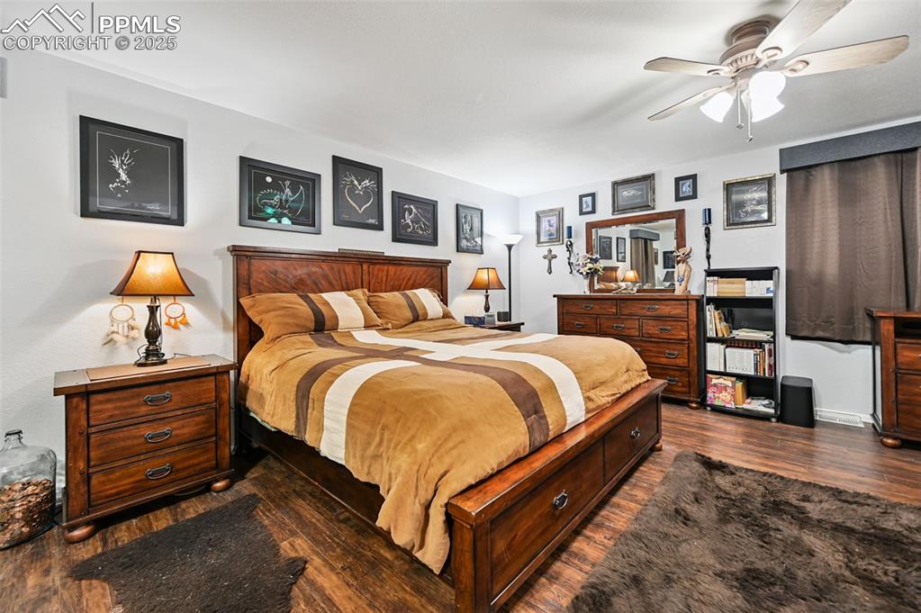 Image 27 of 43: Bedroom with dark wood finished floors and a ceiling fan