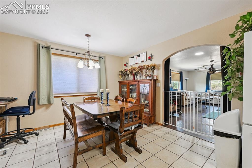 Image 5 of 43: Dining room with arched walkways, light tile patterned floors, ceiling fan,