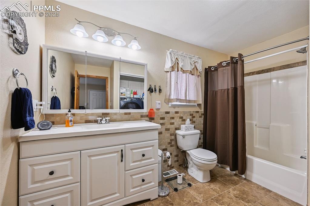 Image 9 of 43: Bathroom featuring vanity, shower / tub combo, and tile walls