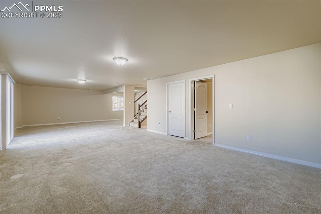 Image 17 of 31: Empty room with stairway and light carpet