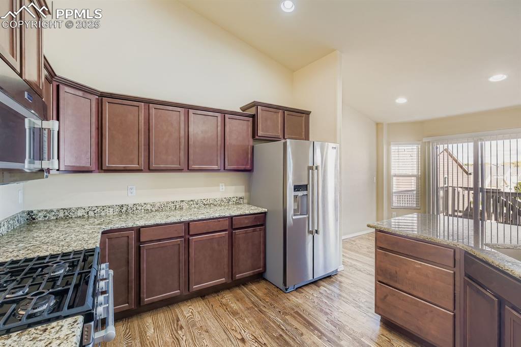 Image 7 of 31: Kitchen featuring light stone countertops, stainless steel appliances, ligh