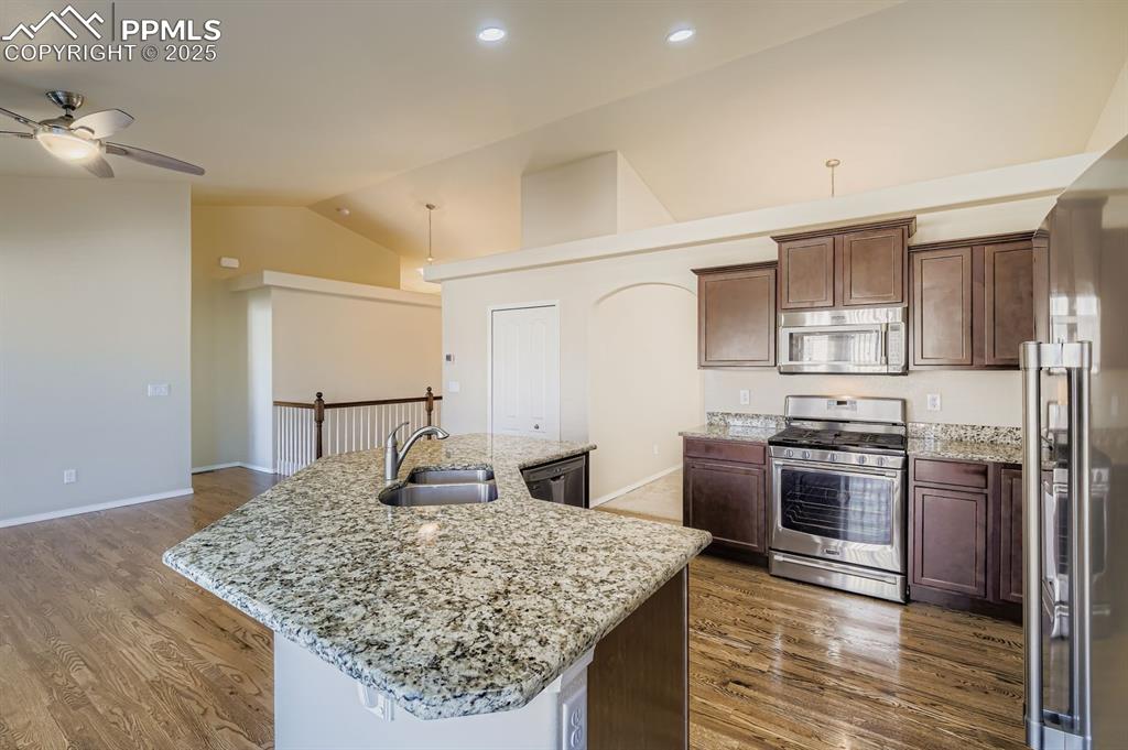 Image 8 of 31: Kitchen featuring lofted ceiling, stainless steel appliances, light stone c