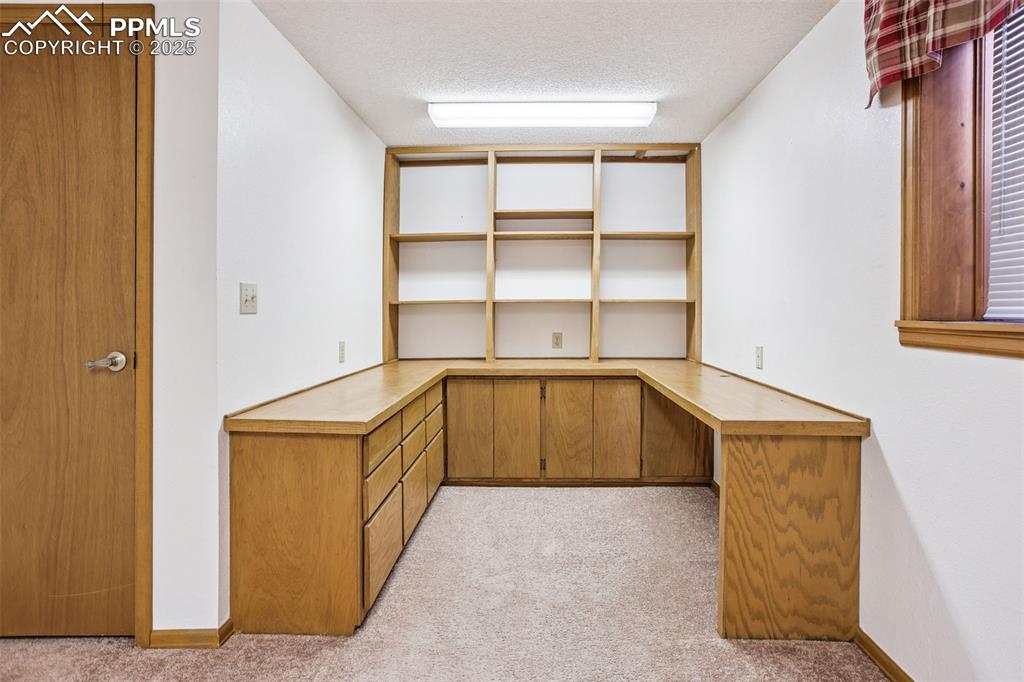Image 23 of 29: basement bedroom with built in desk, can be great office.