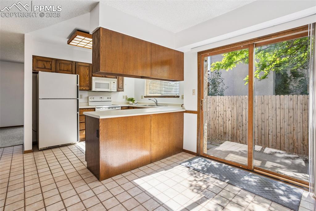 Image 9 of 29: Kitchen-dining area with slider door to side patio