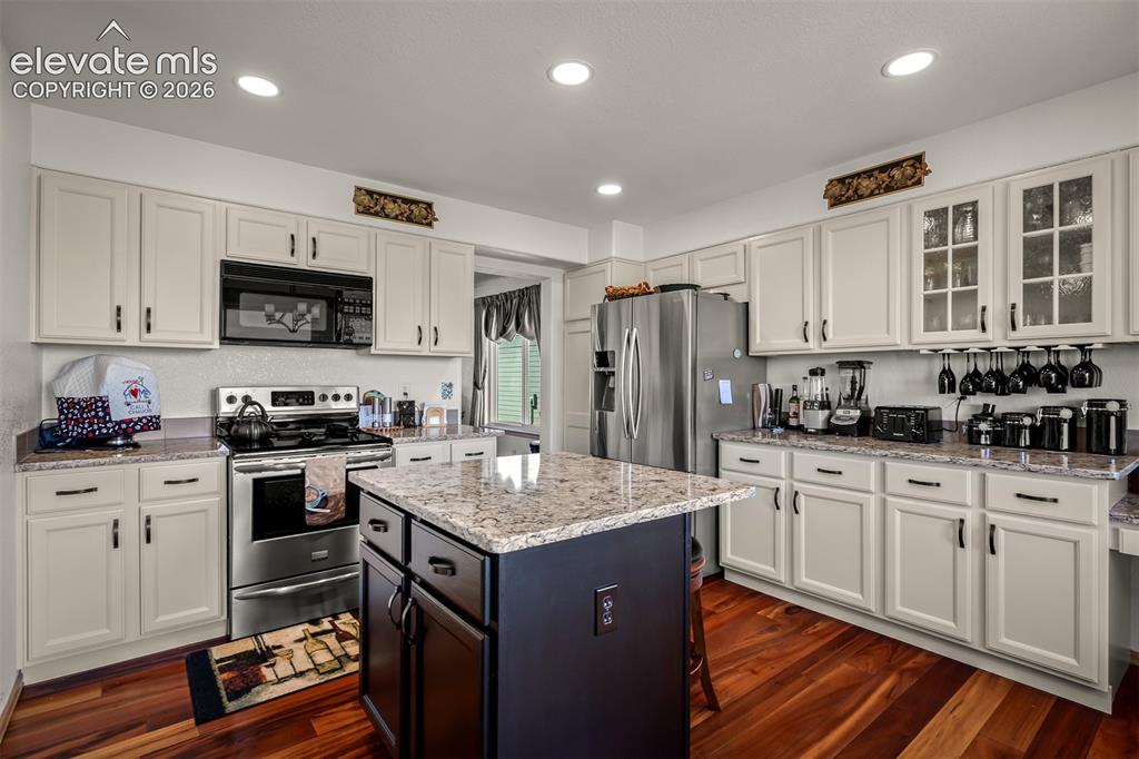 Image 10 of 50: Kitchen featuring a central island with a quartz countertop, light-colored