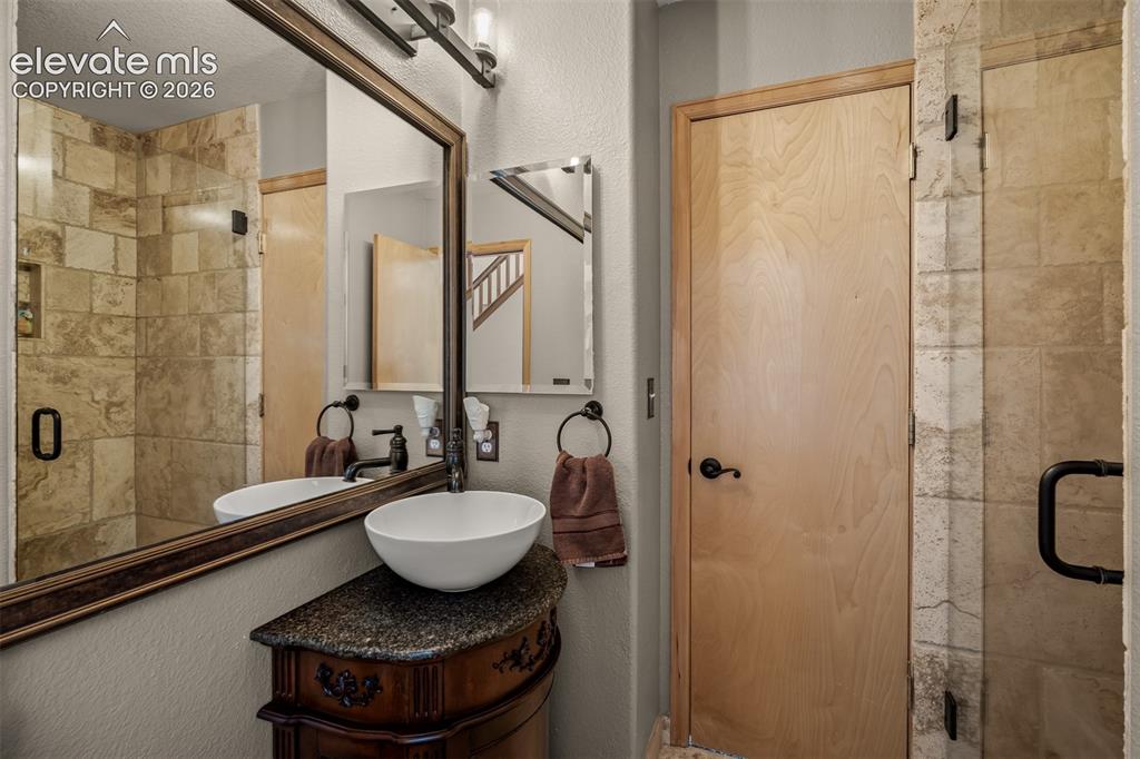 Image 23 of 50: Modern vanity with a vessel sink and dark stone countertop in the main floo