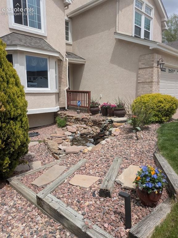 Image 3 of 50: Front yard landscaping featuring a stone water feature, decorative rocks, a
