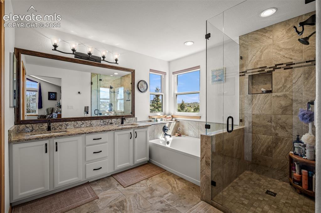 Image 32 of 50: Spacious bathroom featuring a frameless glass shower enclosure with tile su