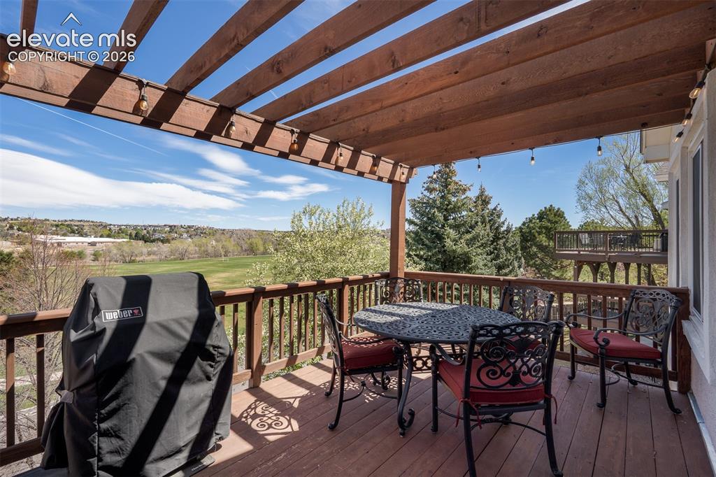 Image 39 of 50: Expansive outdoor upper deck featuring a wood pergola and string lighting.