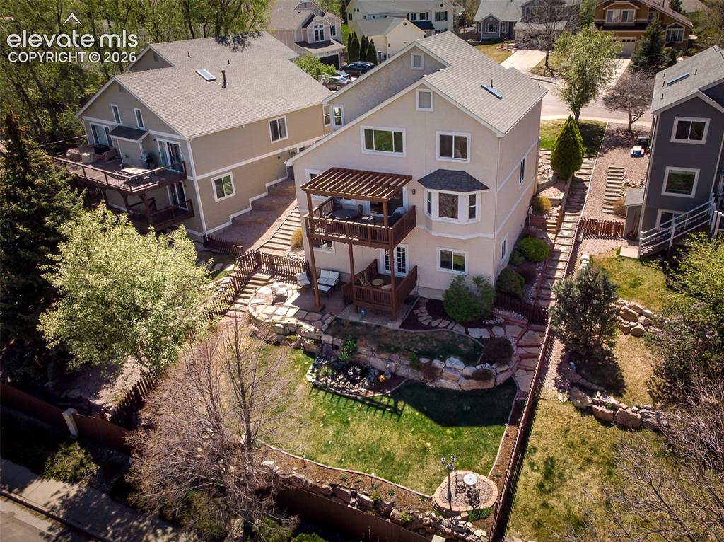 Image 47 of 50: View of back yard with terraced landscaping and mature trees