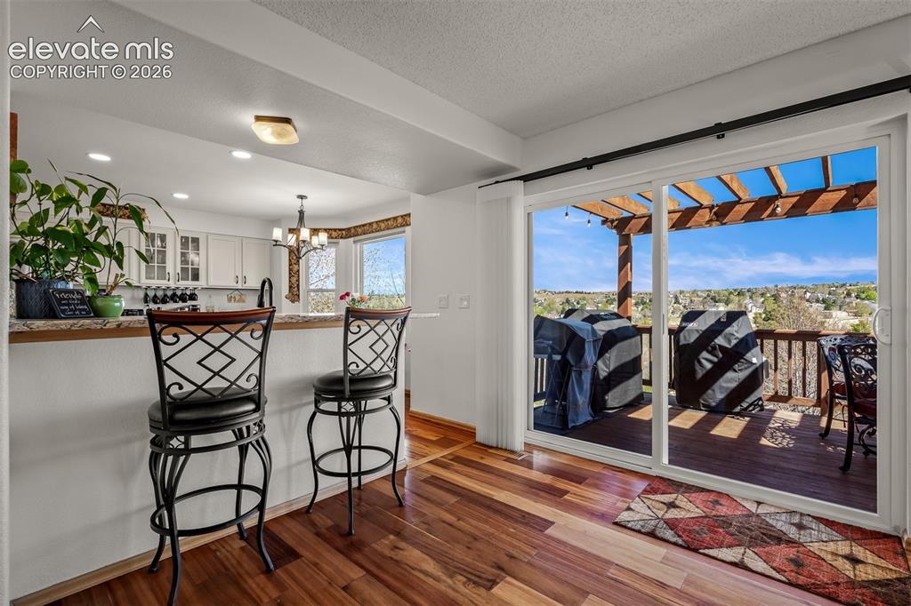 Image 8 of 50: Wide sliding glass doors open to the upper outdoor deck with a pergola and 